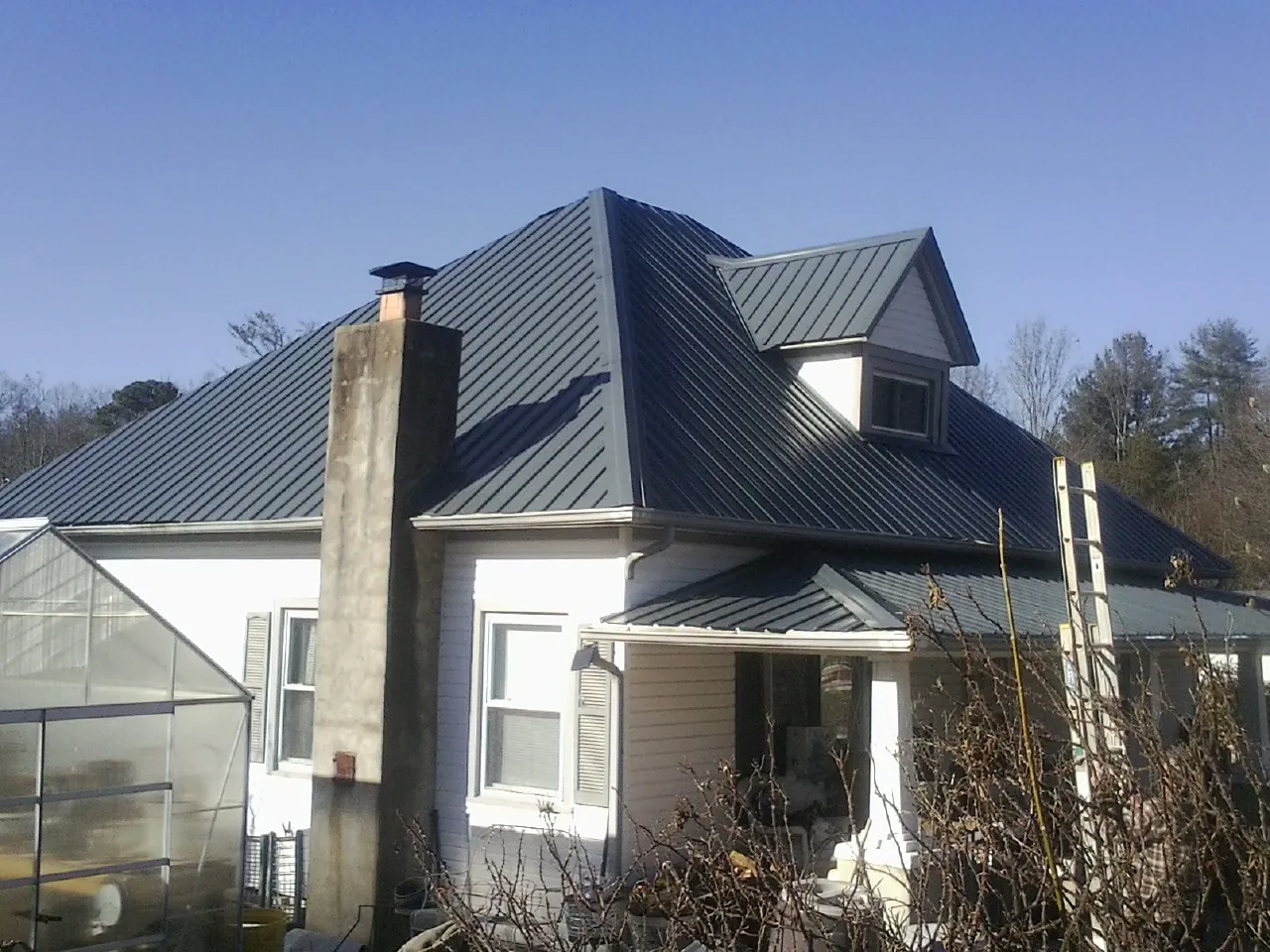 Dark blue standing seam metal roof on a white farmhouse with dormer — Slate & Tile Roof Repair by Roofing Brothers in Blairsville