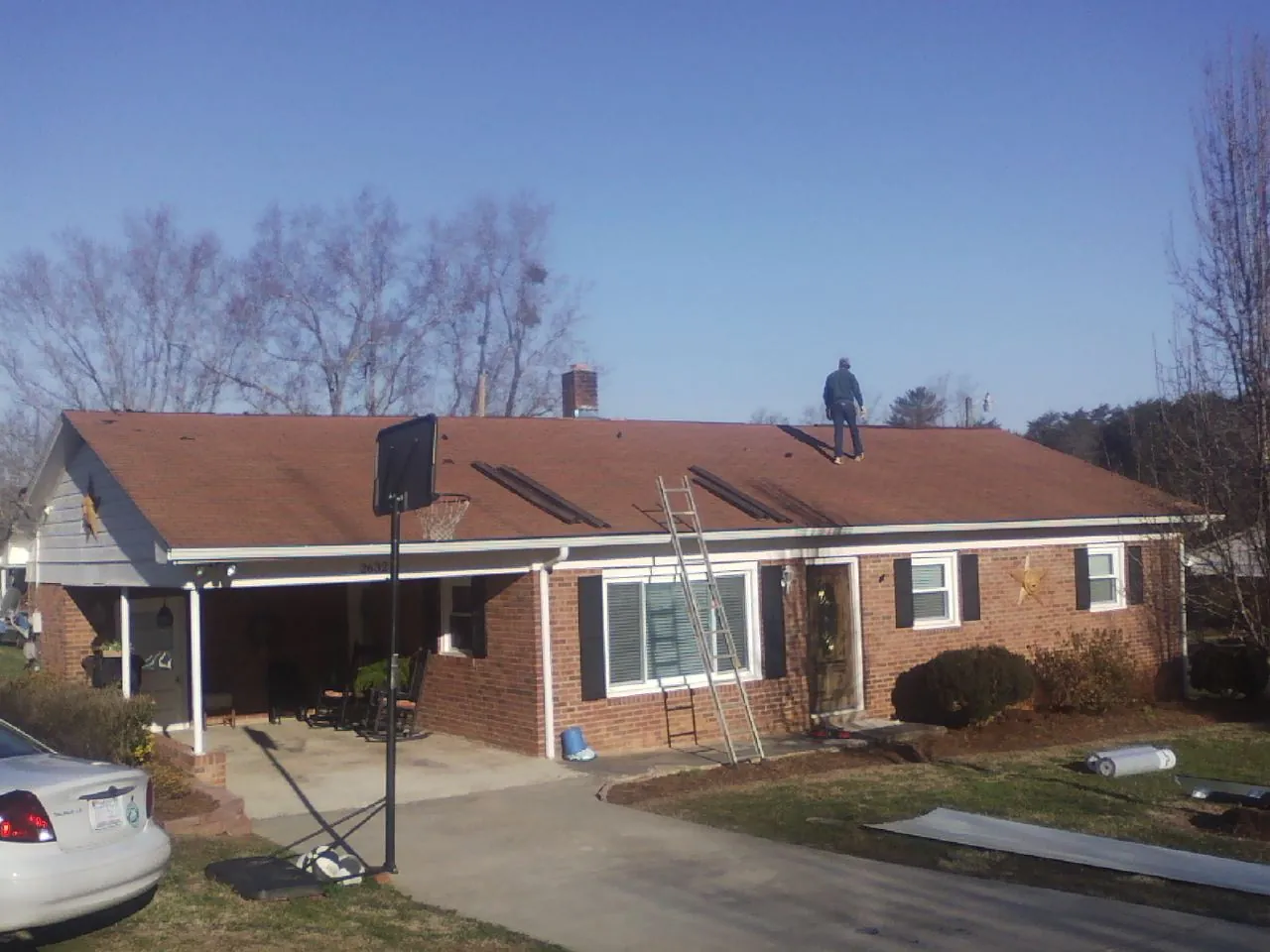 Roofer stripping a shingle roof on a brick ranch before metal panels in Blairsville