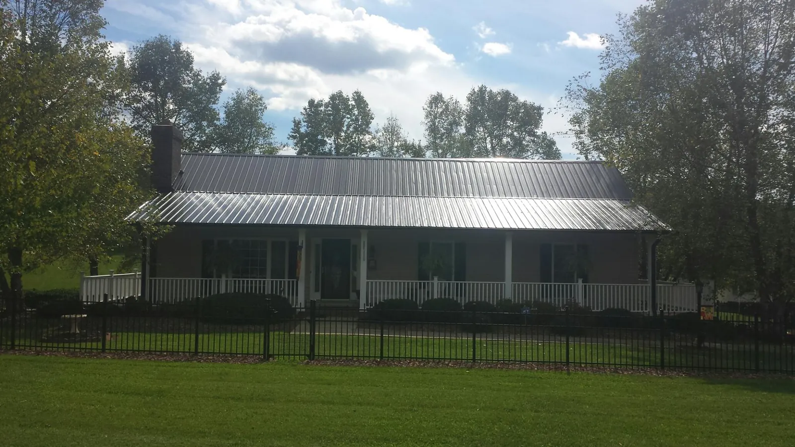 Gray metal roof on a brick ranch with a full width front porch — Gutter Guard Installation work by our crew in Blairsville