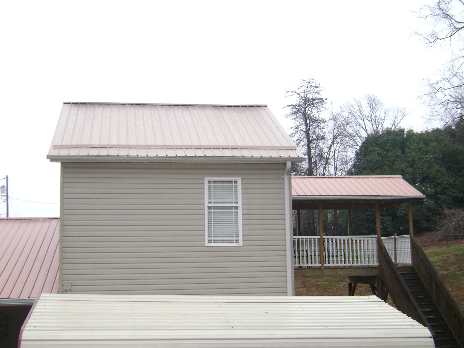 Tan metal roofs on a two story addition and attached porch, from a Roof Replacement job in Blairsville